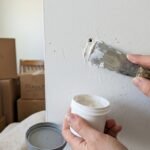 Filling nail holes in a wall with spackle and a putty knife before moving out